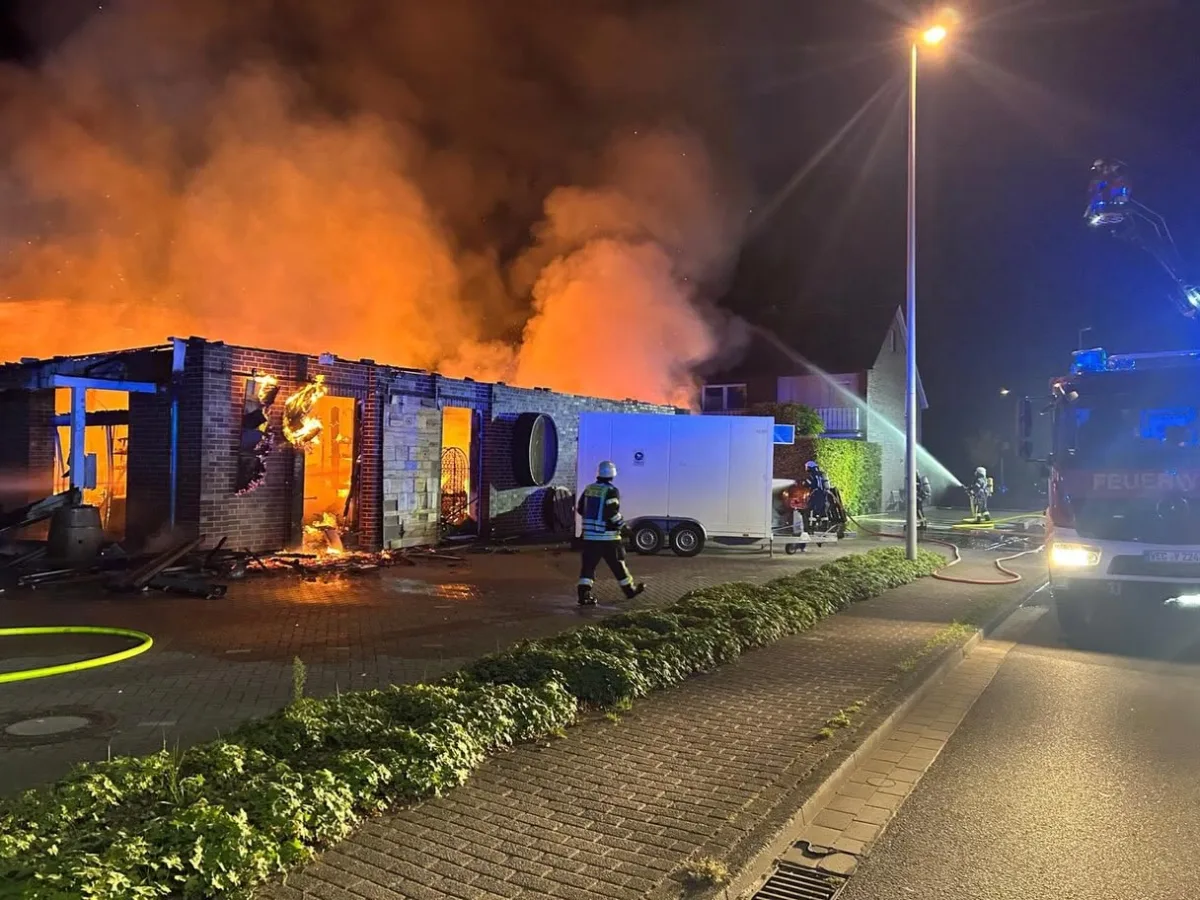 Ein Gebäudebrand wird nachts von der Feuerwehr gelöscht, während Flammen und Rauch aufsteigen.