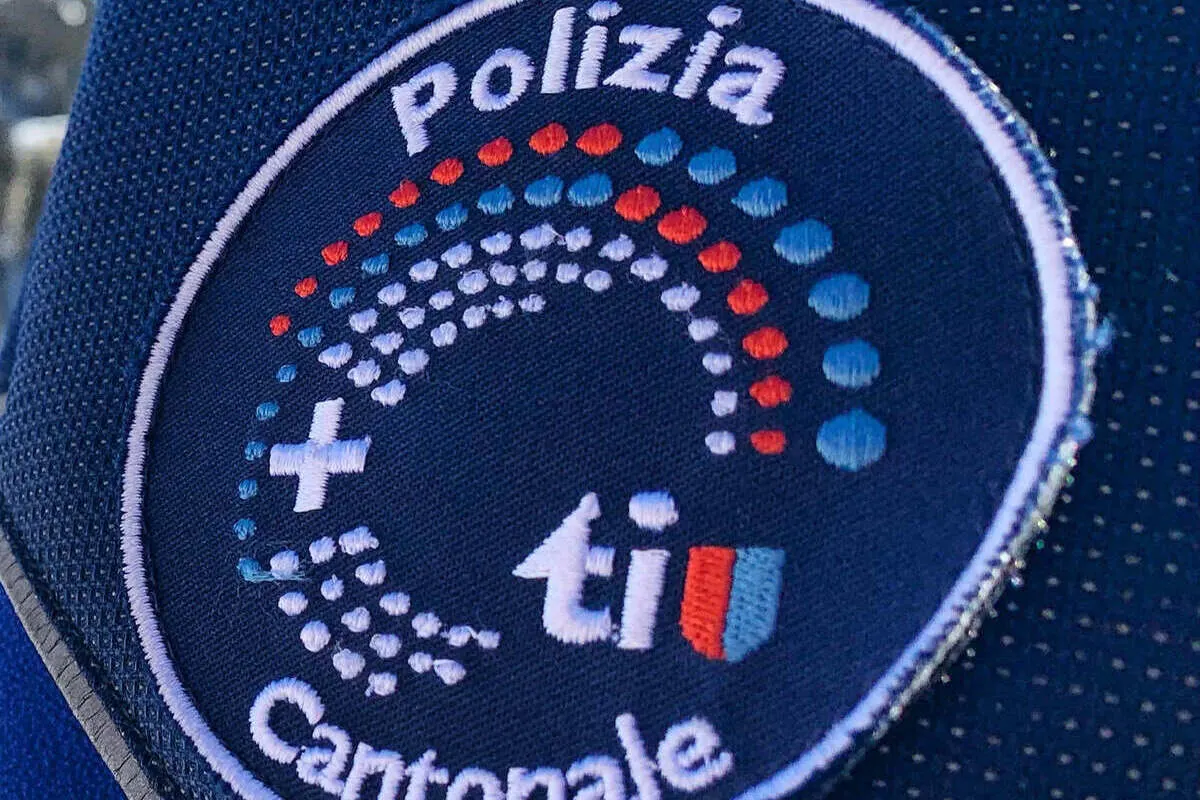 Nahaufnahme eines Polizeiabzeichens der Kantonspolizei Ticino auf einer dunkelblauen Uniform.