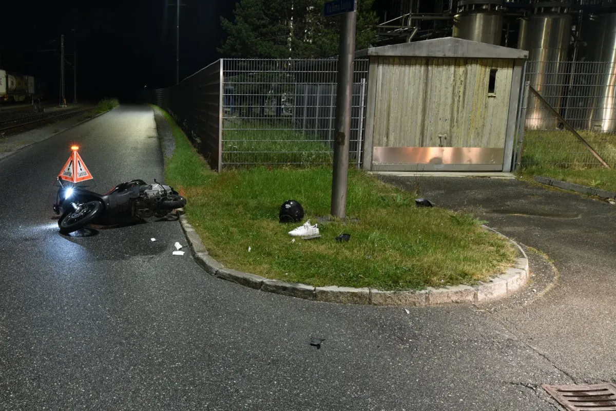Ein Motorrad liegt umgestürzt auf einer Straße neben einem Warndreieck bei Nacht. Auf dem Boden liegt ein Helm und ein Schuh.