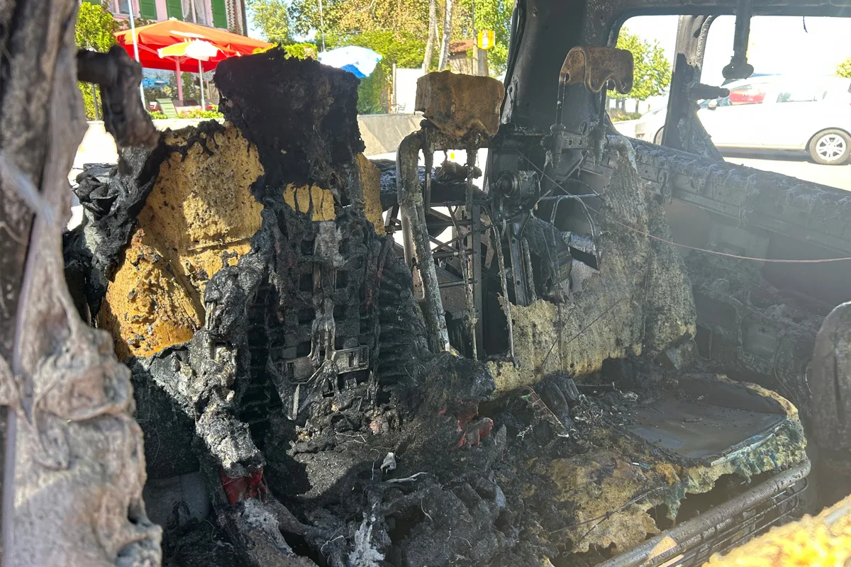 Der Innenraum eines Fahrzeugs zeigt schwere Brandschäden mit verkohlten Sitzen und Strukturen.