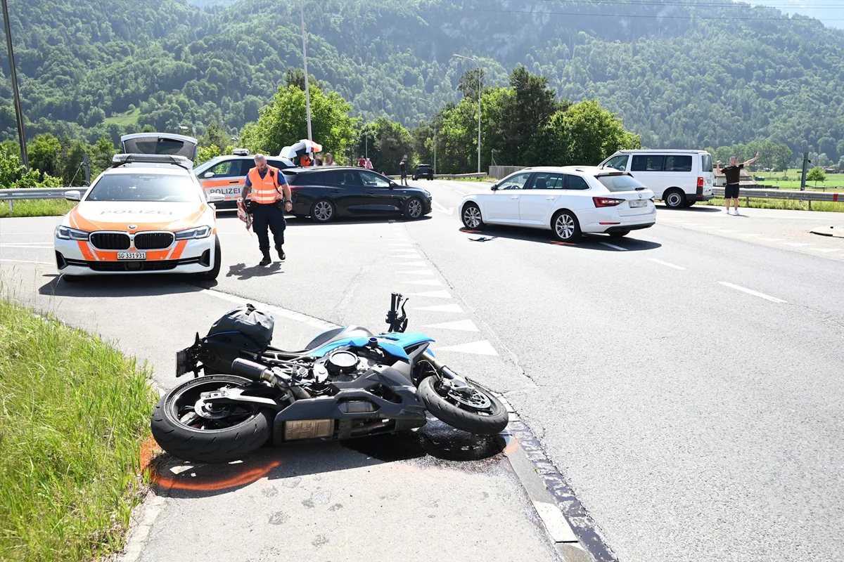Ein umgestürztes Motorrad liegt am Straßenrand neben einem Polizeifahrzeug. Im Hintergrund sind weitere Autos und ein Polizist sichtbar.