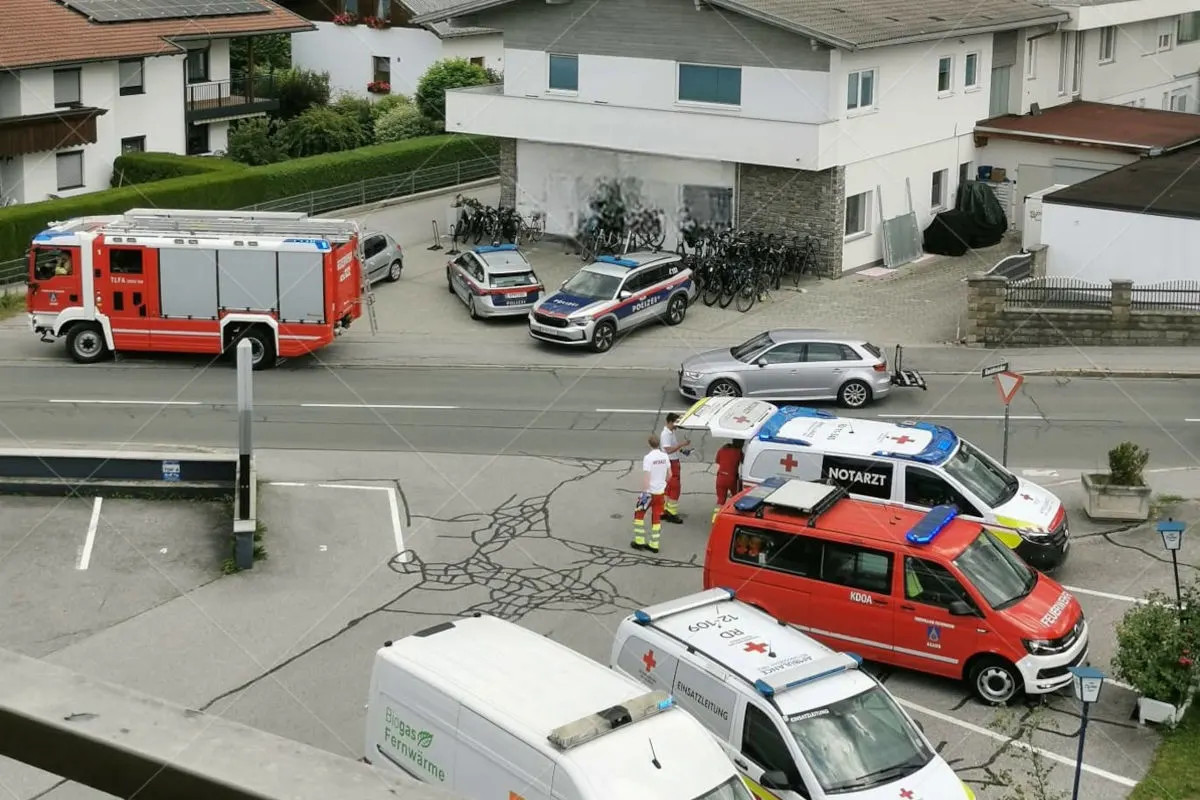 Vor einem Gebäude stehen mehrere Einsatzfahrzeuge von Polizei und Rettungsdienst. Personen in Uniform sind ebenfalls vor Ort.