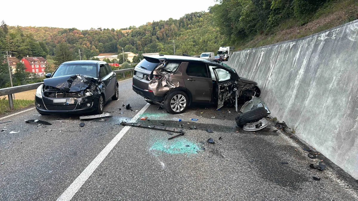 Zwei Fahrzeuge stehen stark beschädigt auf einer Straße, umgeben von Trümmerteilen. Die Szene wirkt verlassen, ohne Personen in der Nähe.