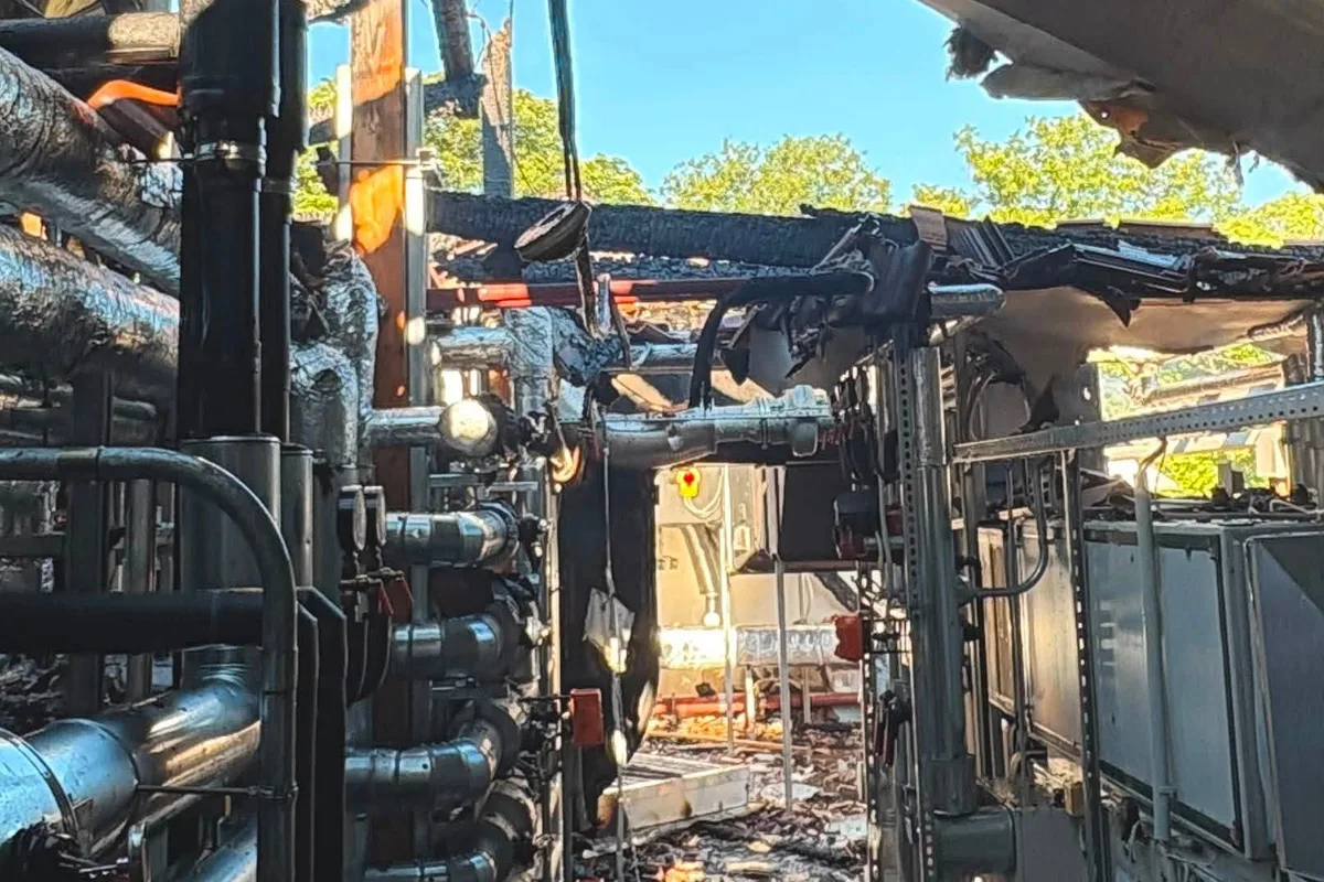Die verkohlten Überreste eines industriellen Gebäudes zeigen sichtbare Stahlstrukturen unter freiem Himmel, mit Schäden durch ein Feuer.