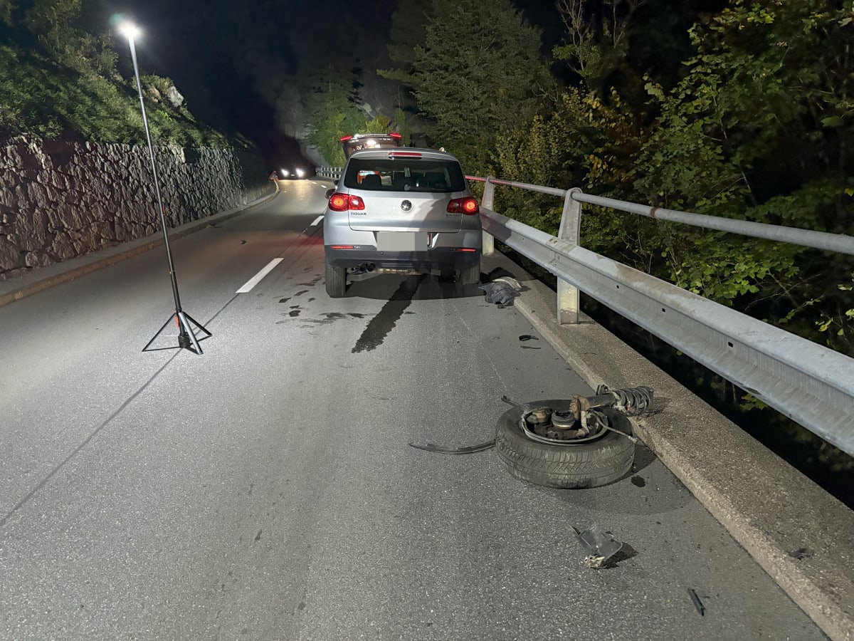 Ein silberner VW Golf steht auf einer unbeleuchteten Landstraße. Ein Ersatzreifen und Trümmer liegen daneben. Die Szene ist nachts, beleuchtet von Straßenlampen.