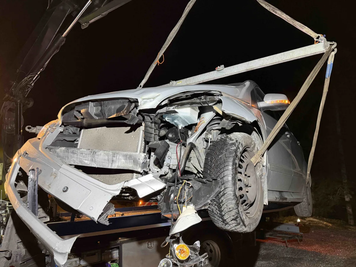Ein stark beschädigtes Auto mit frontalem Schaden wird nachts von einem Abschleppwagen gehoben. Das Auto zeigt erhebliche vordere Beschädigungen.