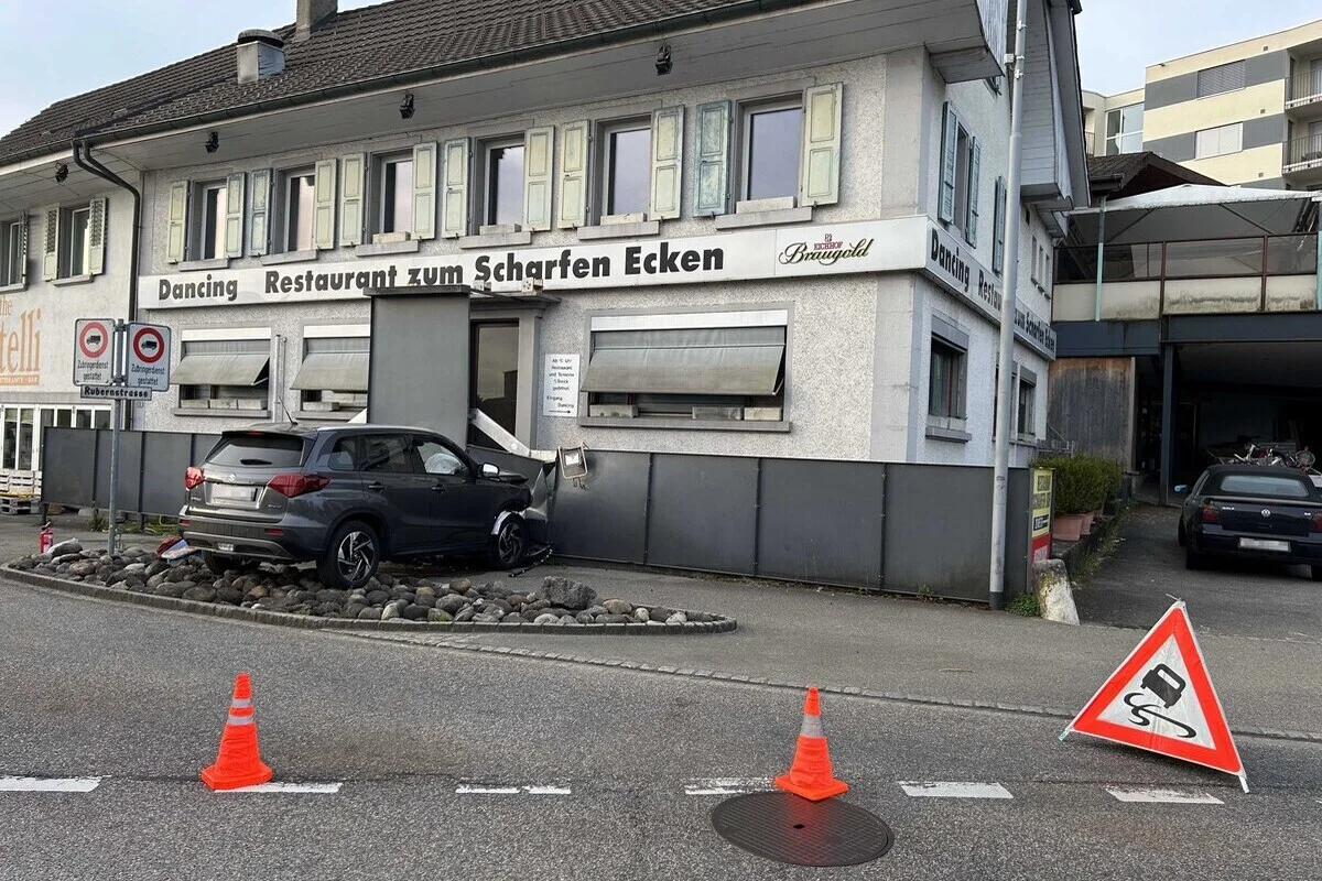 Ein Auto ist gegen die Fassade eines Gebäudes mit der Aufschrift 'Dancing Restaurant zum Scharfen Ecken' geprallt. Verkehrsleitkegel stehen auf der Straße.