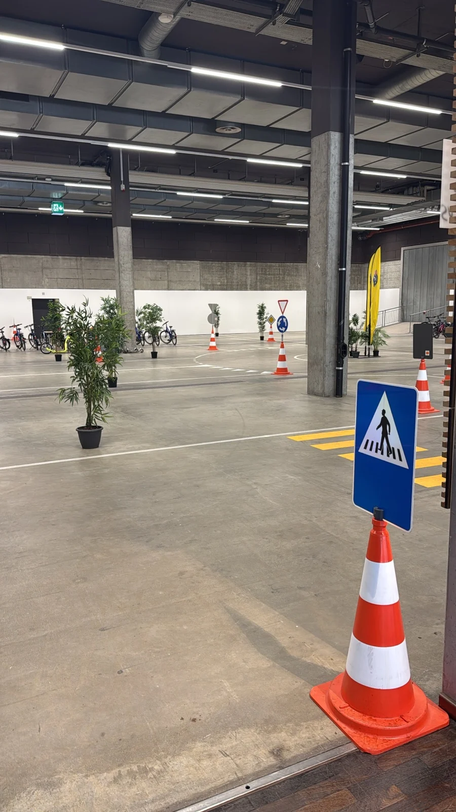 Ein Innenbereich mit einem Verkehrsübungsplatz, markiert durch Verkehrshütchen und Schilder, simuliert realistische Verkehrssituationen.