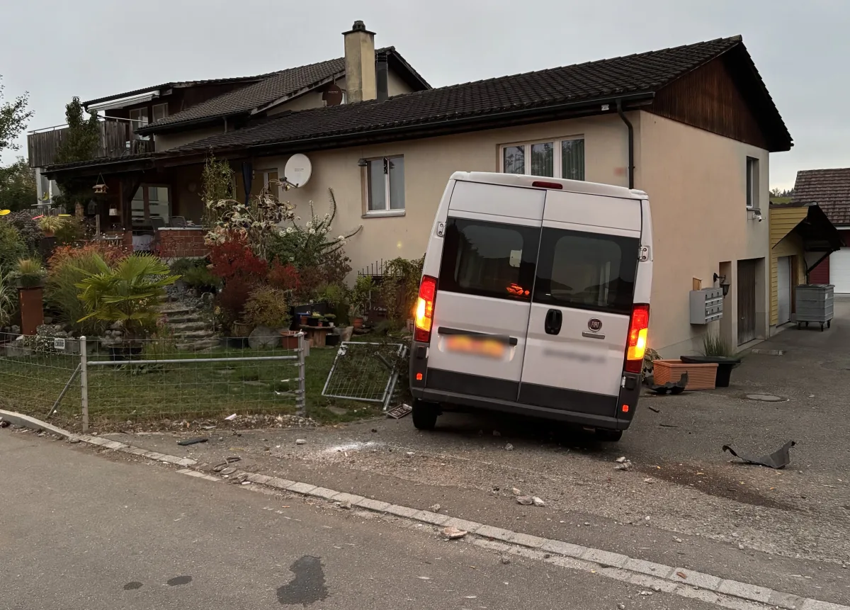 Ein weißer Lieferwagen steckt im Gartenzaun vor einem Einfamilienhaus. Der Zaun ist beschädigt und Schutt liegt verstreut.
