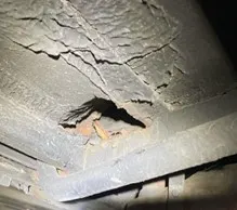 Eine Nahaufnahme zeigt einen stark verrosteten Metallträger mit einem Loch, das strukturelle Schäden aufweist.