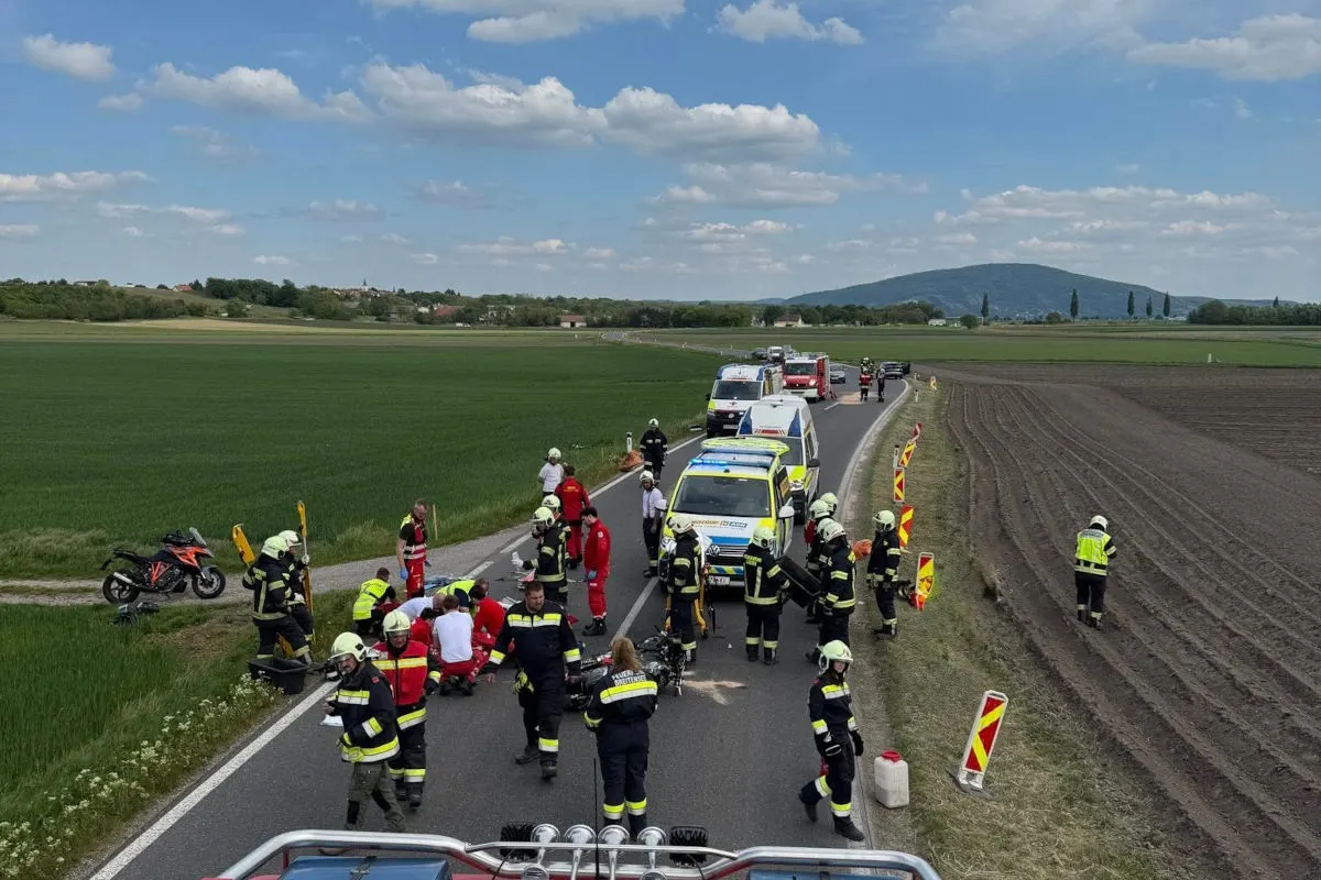 Auf einer Landstraße sind mehrere Einsatzkräfte und Rettungsfahrzeuge zu sehen. Ein Motorrad steht am Straßenrand. Die Umgebung ist ländlich und unter freiem Himmel.