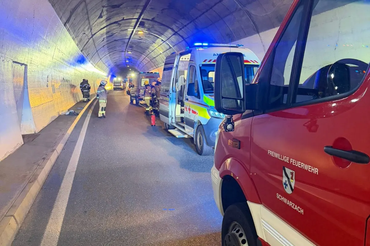 In einem Tunnel stehen Einsatzfahrzeuge der Feuerwehr und des Rettungsdienstes mit eingeschaltetem Blaulicht. Mehrere Feuerwehrleute sind ebenfalls anwesend.