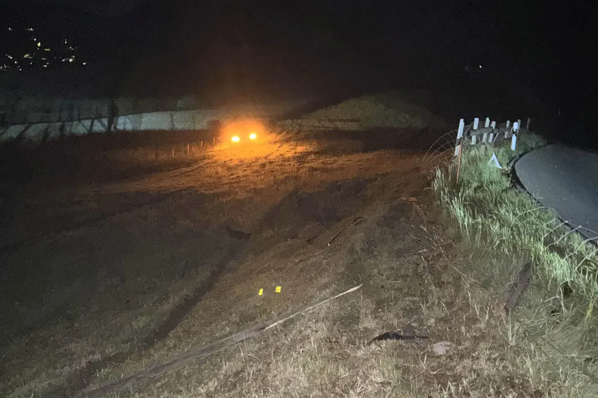 Bei Nacht sind die Scheinwerfer eines Fahrzeugs sichtbar, die eine dunkle Straße und einen Abhang beleuchten. Keine weiteren Objekte oder Personen sind erkennbar.