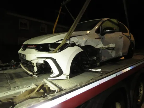 Ein stark beschädigter weißer Pkw befindet sich auf einem Abschleppwagen. Das Fahrzeug zeigt erhebliche Front- und Seitenschäden.