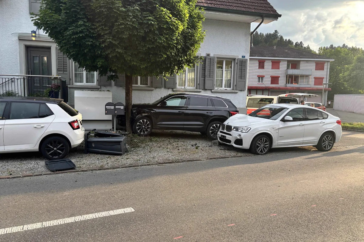 Mehrere Fahrzeuge vor einem Wohnhaus; ein SUV ist gegen das Gebäude geprallt, andere Autos stehen daneben.