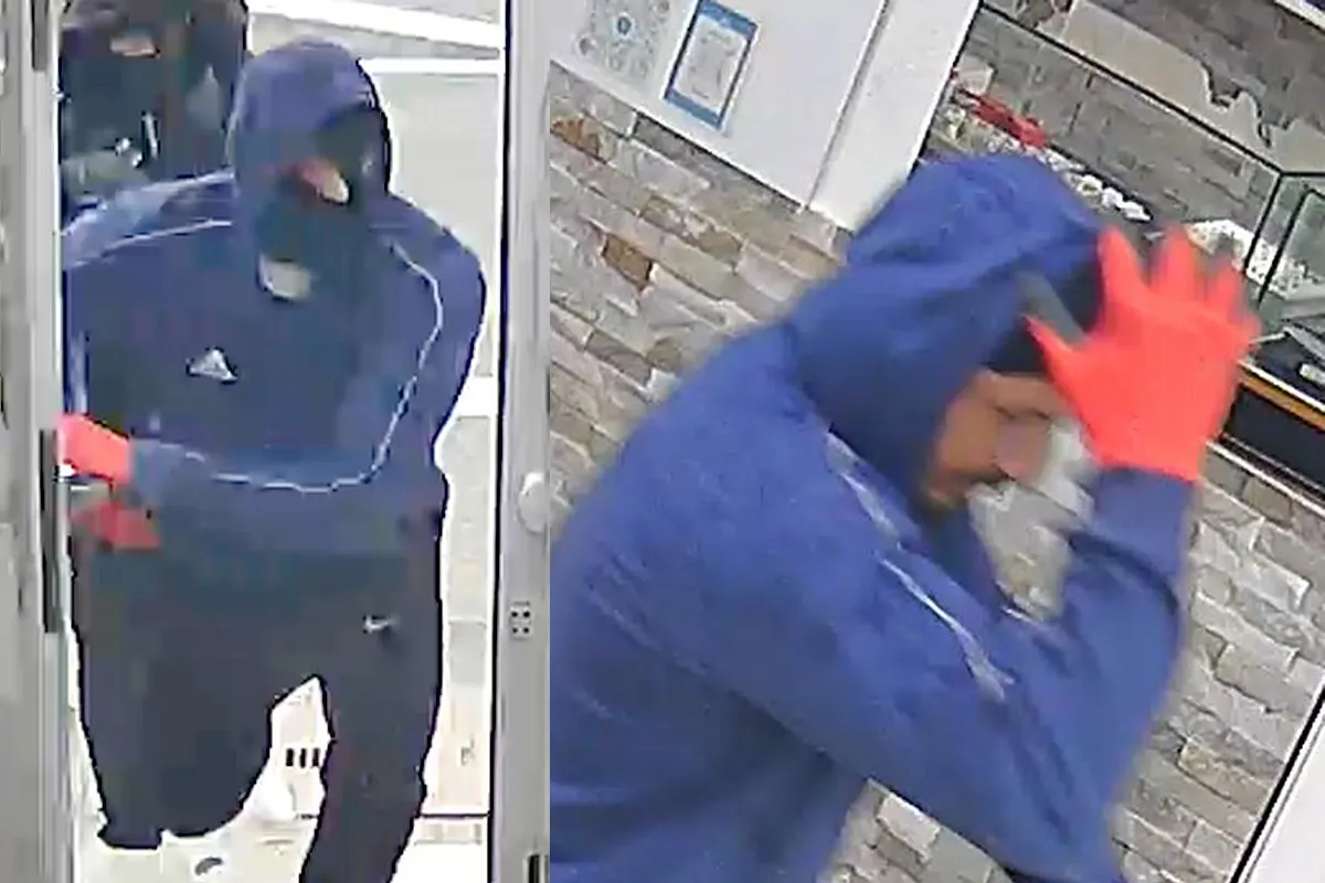Zwei Personen in blauen Kapuzen und rote Handschuhe, eine betritt einen mit Steinwänden gestalteten Raum durch eine Tür.