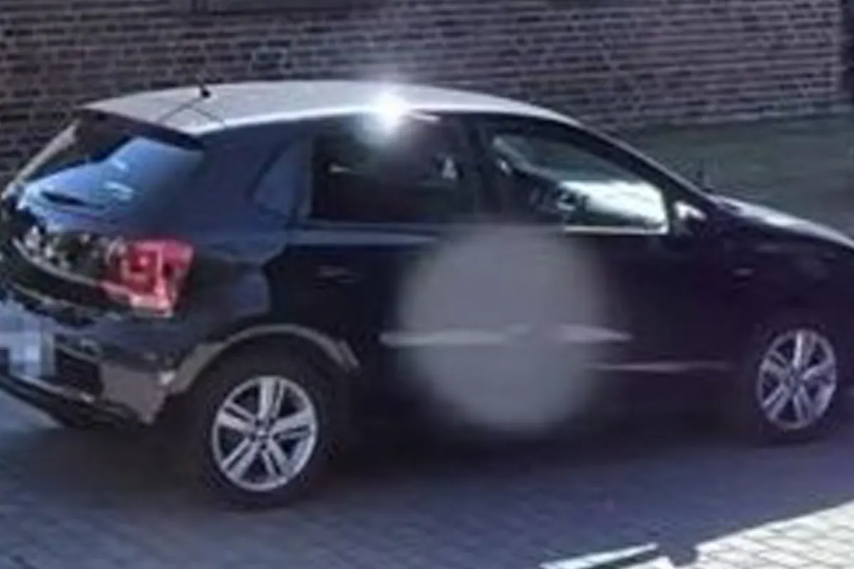Ein schwarzer VW Kleinwagen parkt auf einer gepflasterten Fläche vor einer Backsteinmauer. Die Sonne reflektiert auf der Windschutzscheibe.