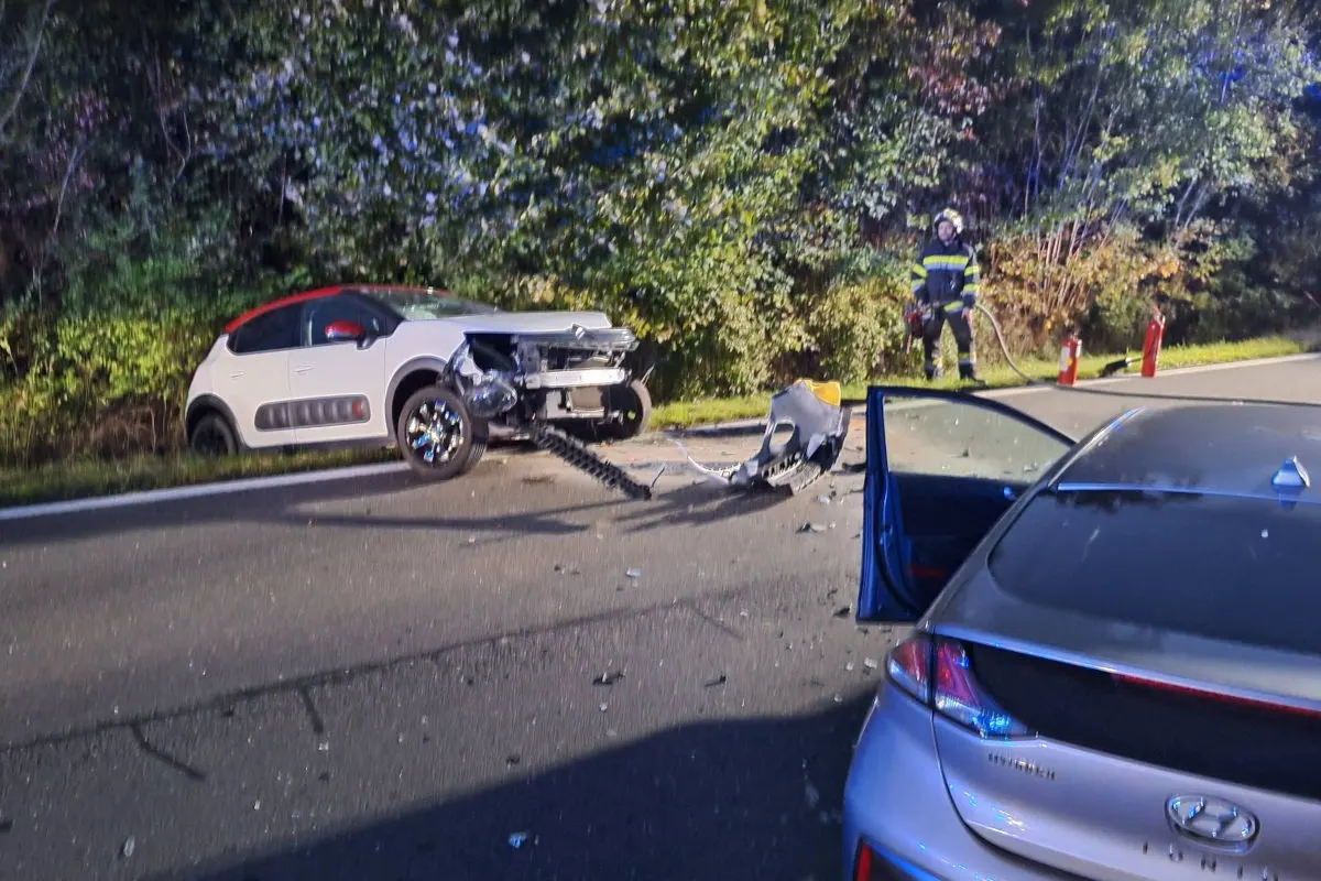 Ein stark beschädigter weißer Citroën steht am Straßenrand, während ein beschädigter blauer Hyundai mit offener Tür auf der Straße steht. Ein Feuerwehrmann ist im Hintergrund sichtbar.
