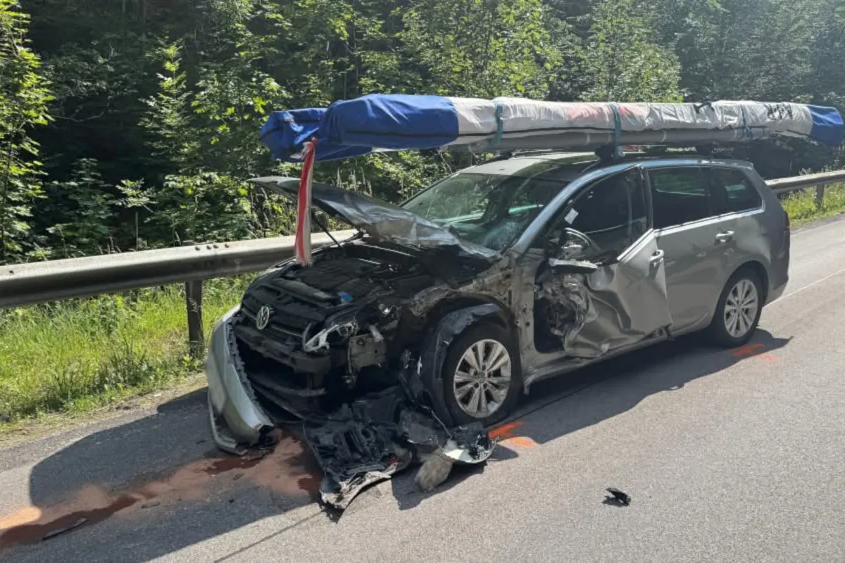 Ein silberner VW Kombi steht beschädigt mit Front- und Seitenschäden auf einer Landstraße. Auf dem Dach befindet sich sicher befestigte Ladung in einer Plane.