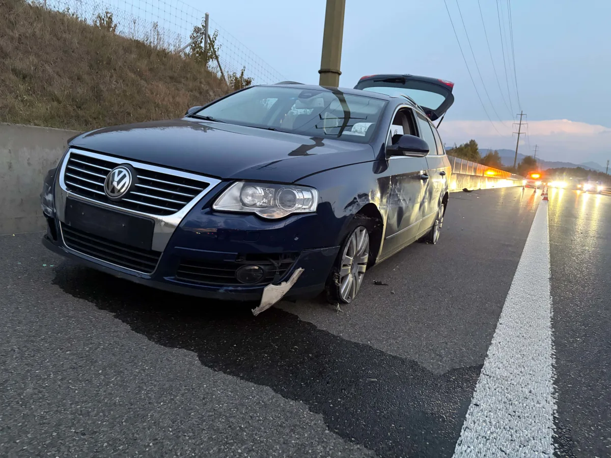Ein blaues VW-Auto steht mit Beschädigungen am Straßenrand einer Autobahn, der Kofferraum ist geöffnet, es ist Dämmerung.