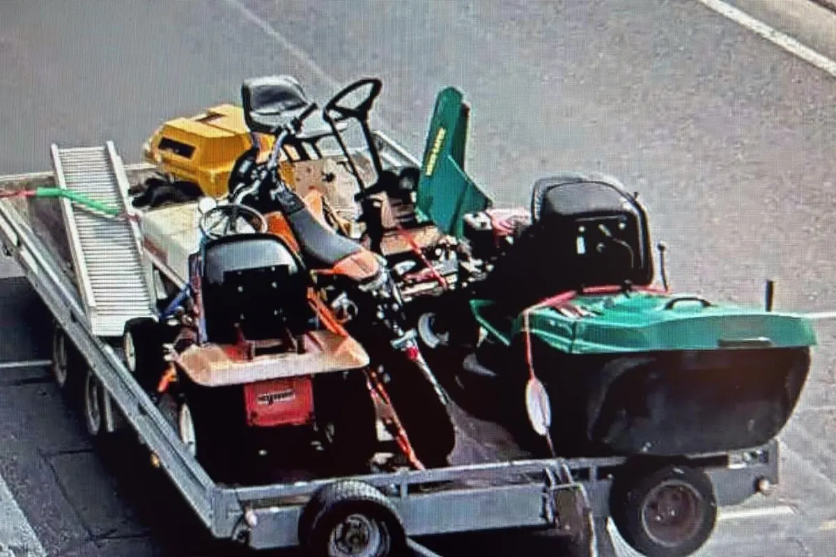Ein Anhänger beladen mit mehreren Aufsitzmähern steht auf einer asphaltierten Straße. Die Mäher sind farblich unterschiedlich gestaltet.