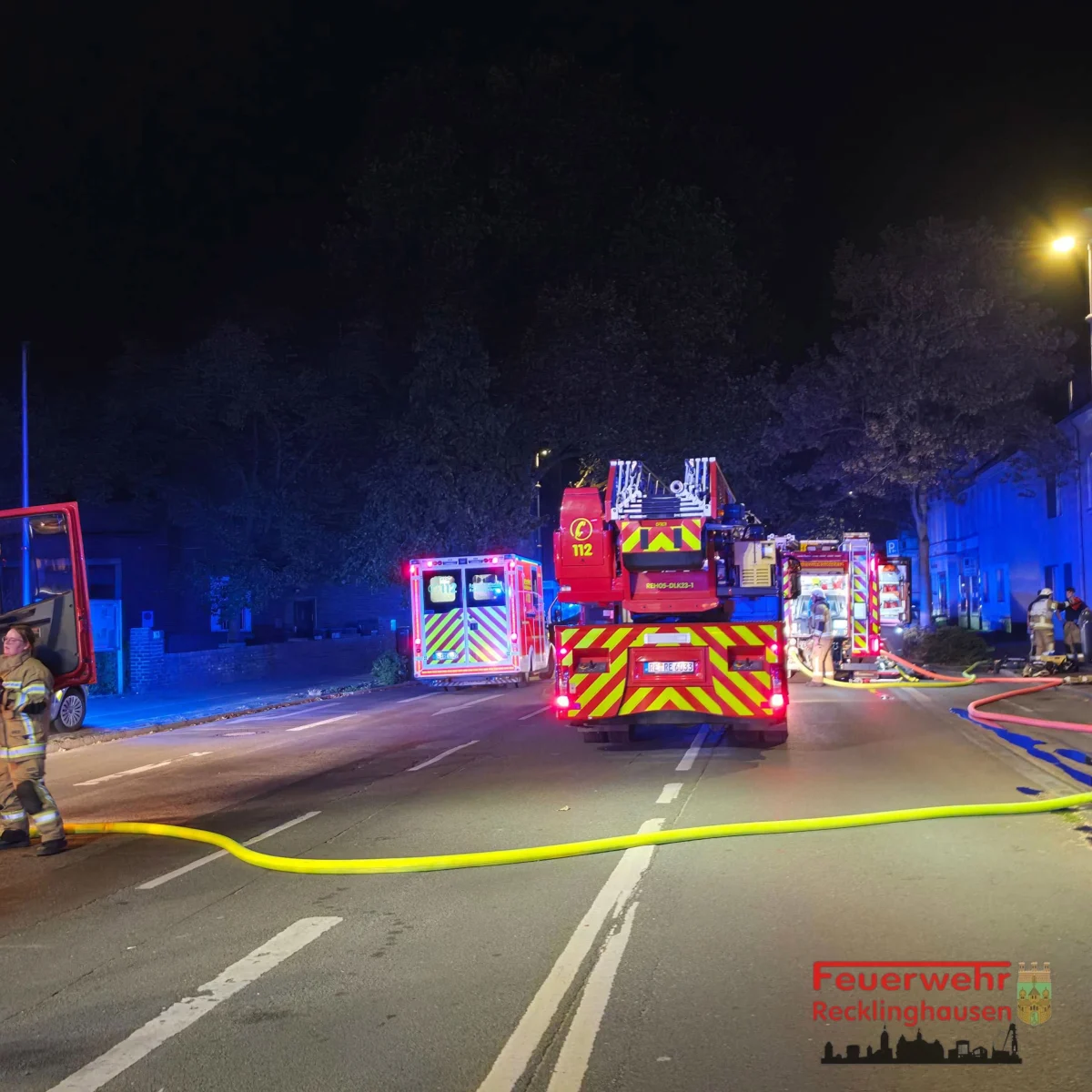 Mehrere Feuerwehrfahrzeuge stehen mit aktivem Blaulicht auf einer nächtlichen Straße. Einsatzkräfte sind sichtbar.