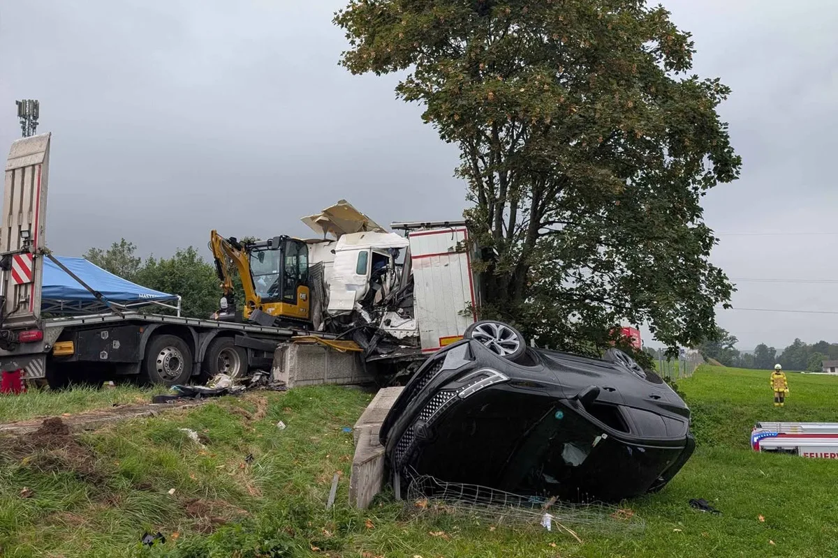 Ein Lkw ist abgestürzt, daneben liegt ein Pkw auf der Seite. Ein Feuerwehrmann steht in der Nähe.