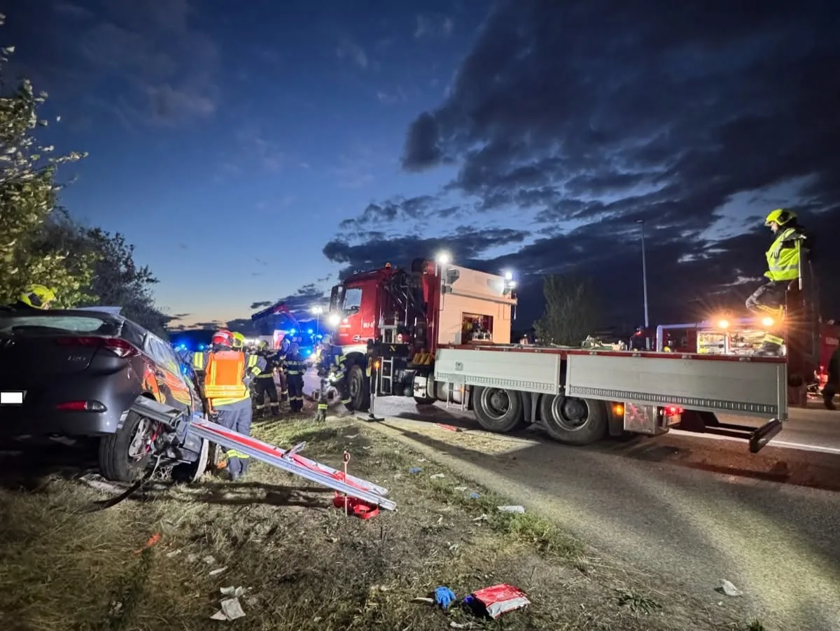 Bei Nacht sichern Einsatzkräfte eine Unfallstelle auf der Straße ab, ein beschädigtes Auto ist zu sehen.