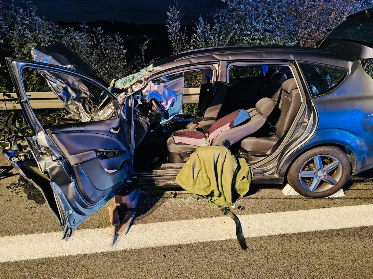Ein Auto mit erheblichen Schäden an der Fahrertür steht auf einer Straße bei Nacht. Türen sind geöffnet und der Innenraum ist sichtbar.