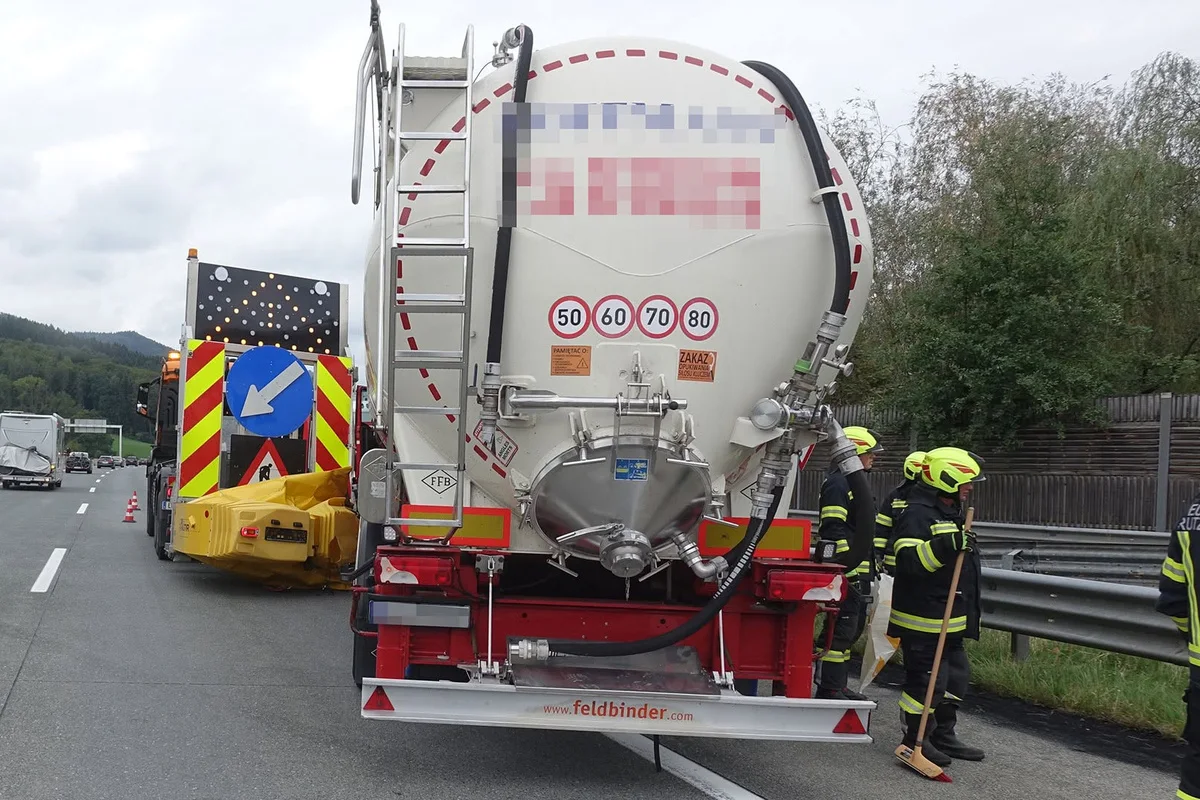 Feuerwehrleute stehen neben einem großen Tankfahrzeug auf einer Autobahn. Im Hintergrund sind Absperrkonen sichtbar.