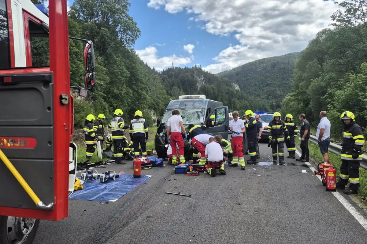 Mehrere Rettungskräfte und Feuerwehrleute sind an einem verunfallten Transporter auf einer Landstraße im Einsatz. Der Transporter ist sichtbar beschädigt, während Ausrüstungsgegenstände auf der Straße verteilt sind.
