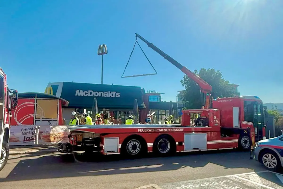 Ein rotes Feuerwehrfahrzeug mit Hebevorrichtung steht vor einem McDonald's. Mehrere Feuerwehrleute sind anwesend.