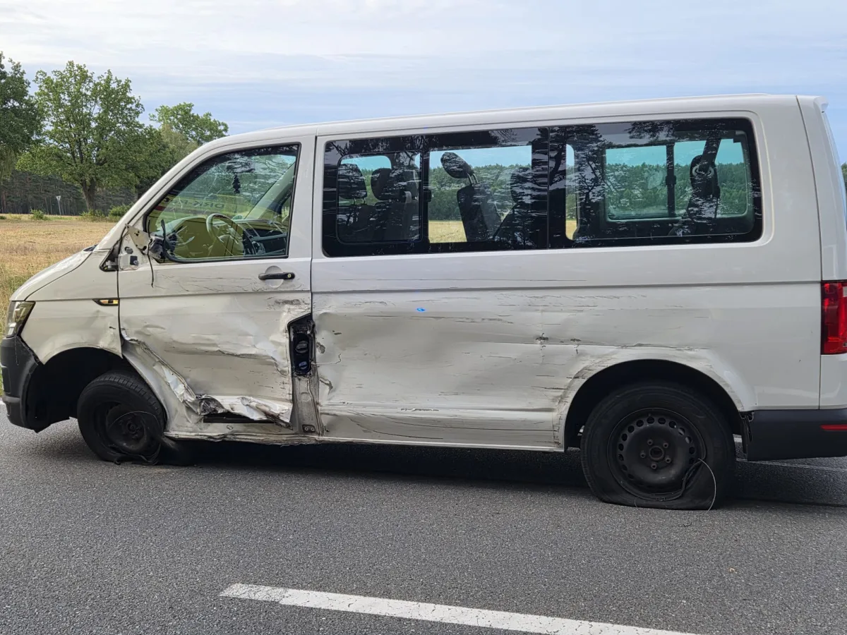 Ein stark beschädigter weißer Transporter steht am Straßenrand. Die linke Fahrzeugseite ist stark eingedellt, mit plattgedrückten Reifen.