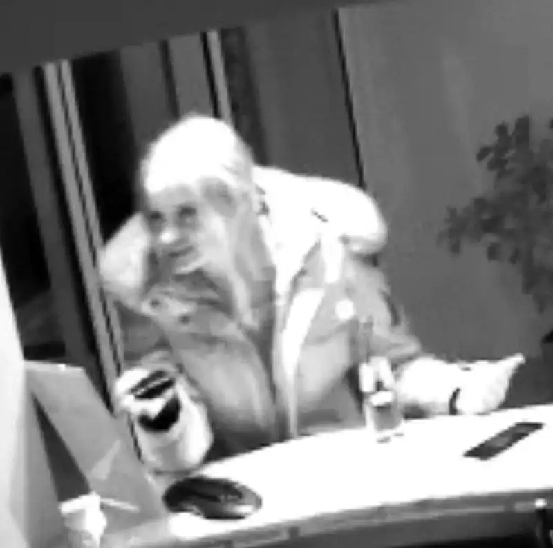 Eine Person im dicken Mantel ist im Foyerbereich zu sehen, aufgenommen von einer Überwachungskamera. Der Hintergrund zeigt Türen und Dekoration.