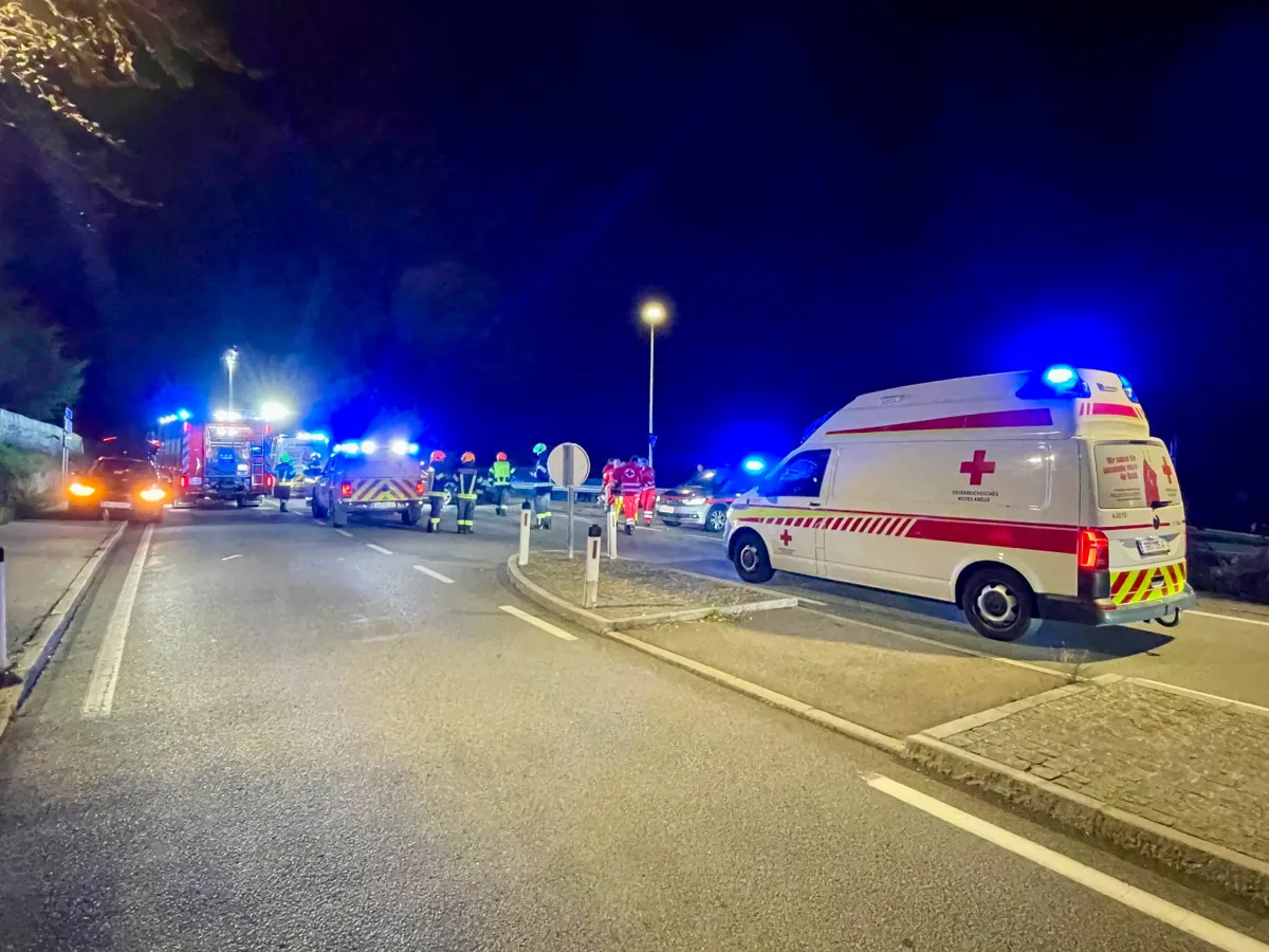 Ein nächtlicher Rettungseinsatz zeigt mehrere Einsatzfahrzeuge auf einer Straße unter Beleuchtung. Feuerwehrleute sind zu sehen.