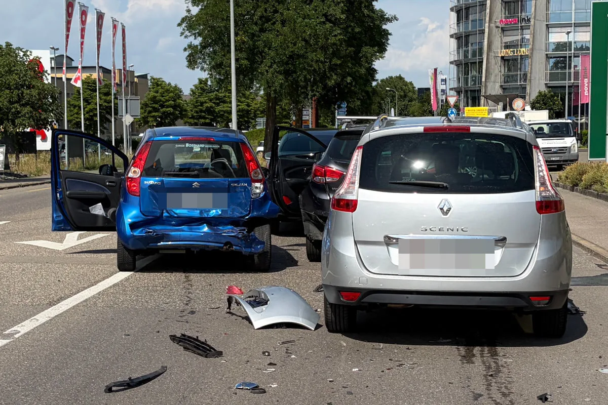 Ein blauer Suzuki und ein silberner Renault stehen beschädigt nach einem Auffahrunfall auf der Straße. Fahrzeugteile liegen verstreut.