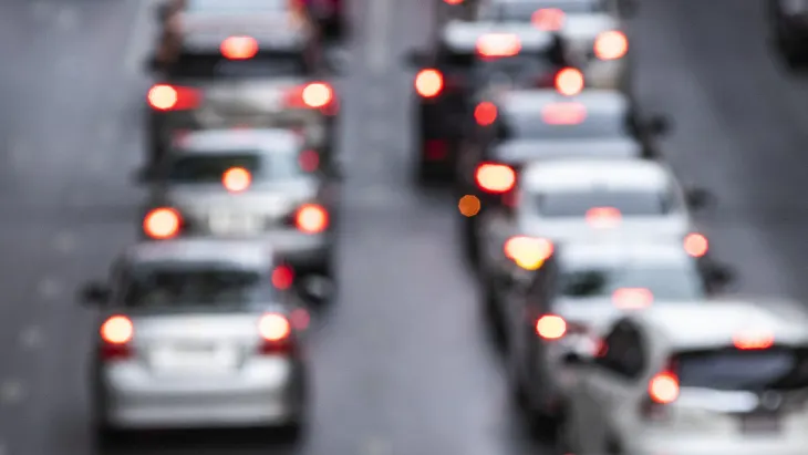 Mehrspurige Straße mit starkem Verkehrsstau, mehrere Autos in beiden Richtungen sichtbar.