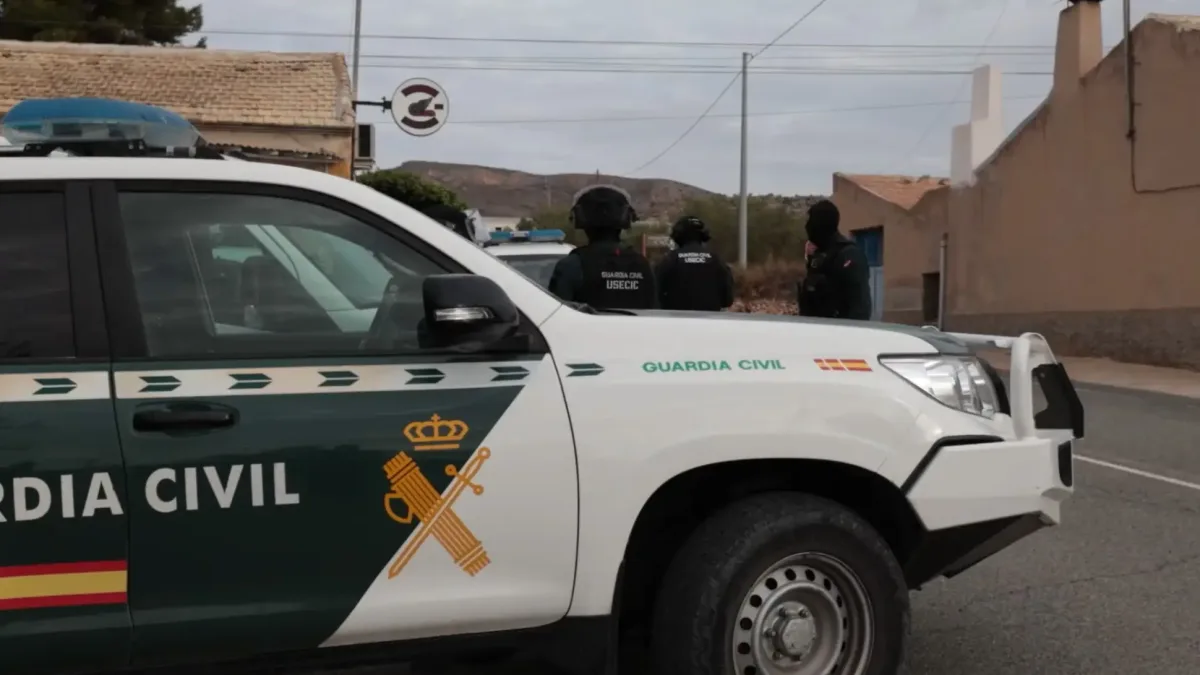 Ein Fahrzeug der Guardia Civil steht auf einer Straße, während zwei uniformierte Beamte im Hintergrund zu sehen sind.