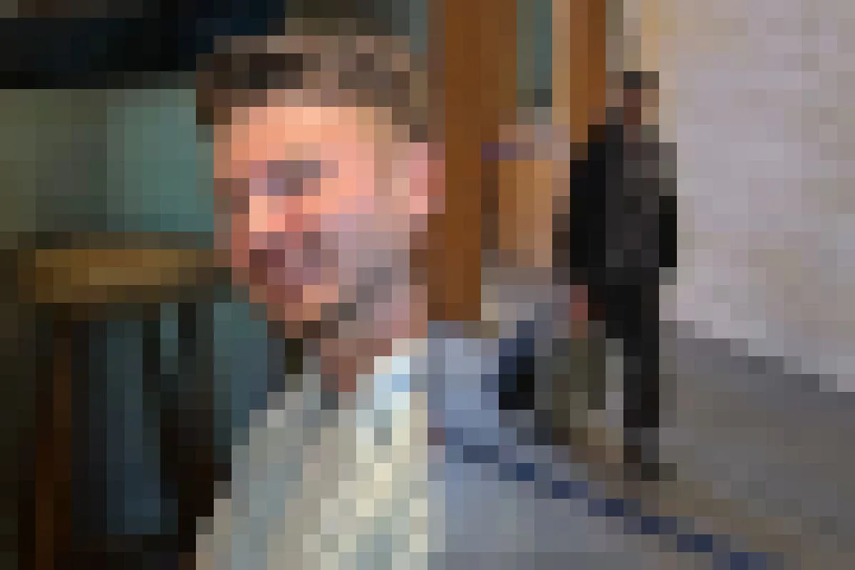 Eine Person steht im Vordergrund in einem Gerichtsflur, unscharfe Details im Hintergrund.