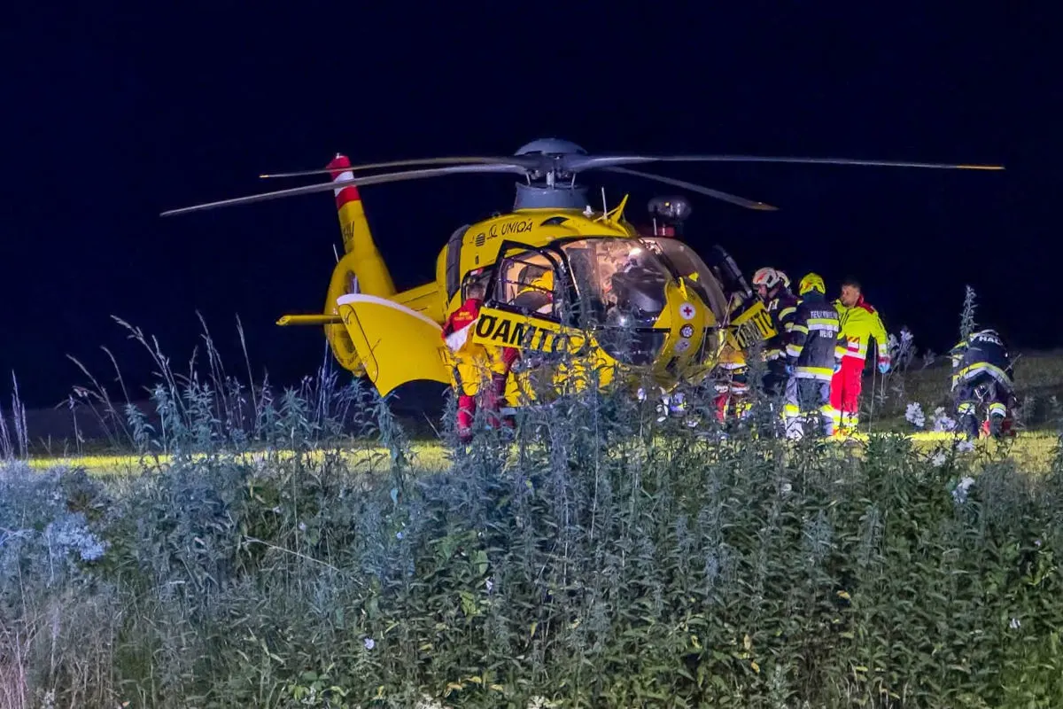 Ein gelber Rettungshubschrauber steht nachts im Gelände. Zahlreiche Einsatzkräfte sind um den Hubschrauber herum aktiv.