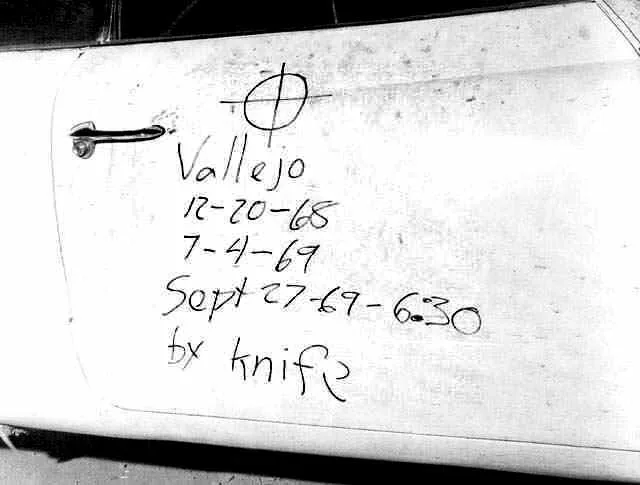 Eine weiße Autotür ist mit einem handgeschriebenen Text in dunkler Schrift versehen, inklusive Daten und einem symbolischen Zeichen.