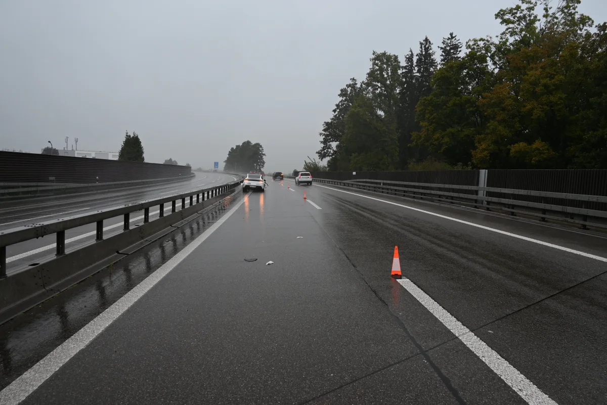 Eine regennasse Autobahn mit mehreren Fahrzeugen. Verkehrshütchen markieren die Fahrbahn.