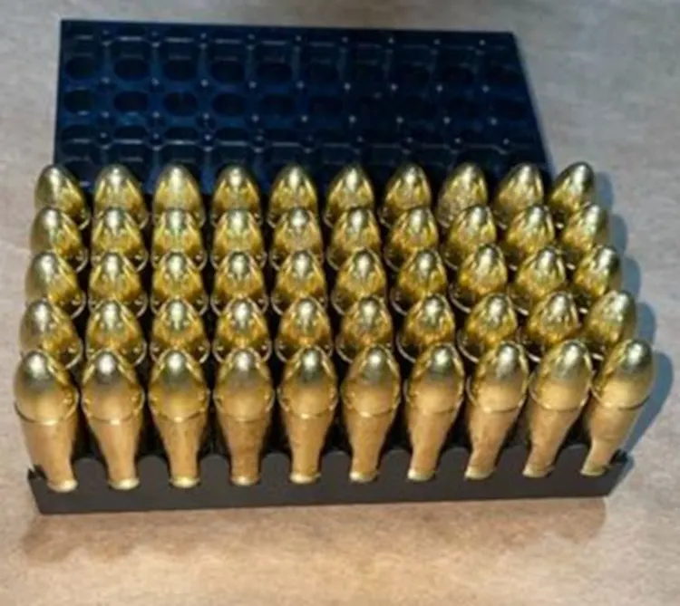 Ein Tablett mit mehreren Reihen von goldfarbenen, glänzenden Geschossen ist zu sehen. Sie sind sorgfältig nebeneinander platziert in einer rechteckigen Formation.
