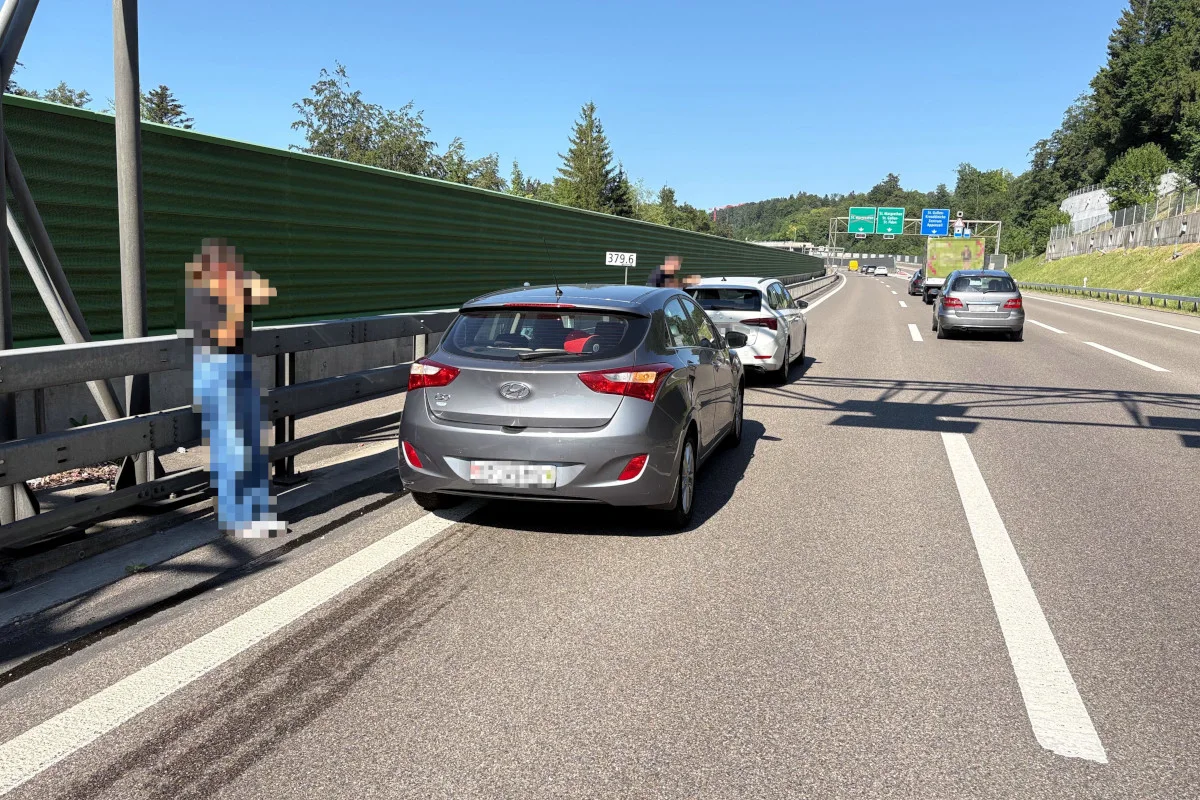 Zwei Autos stehen auf dem Seitenstreifen einer Autobahn. Eine Person steht neben der Leitplanke, eine weitere sitzt im Auto.