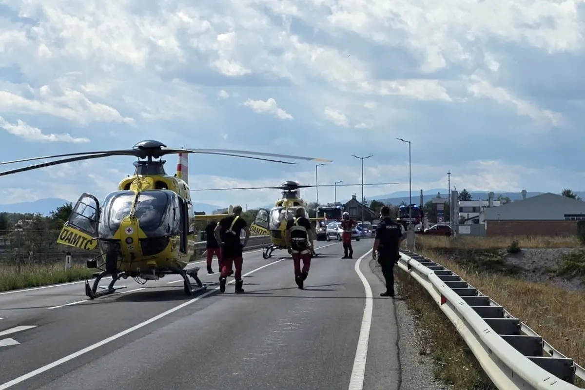 Zwei gelbe Rettungshubschrauber stehen auf einer Landstraße, umgeben von Polizei und Rettungskräften.