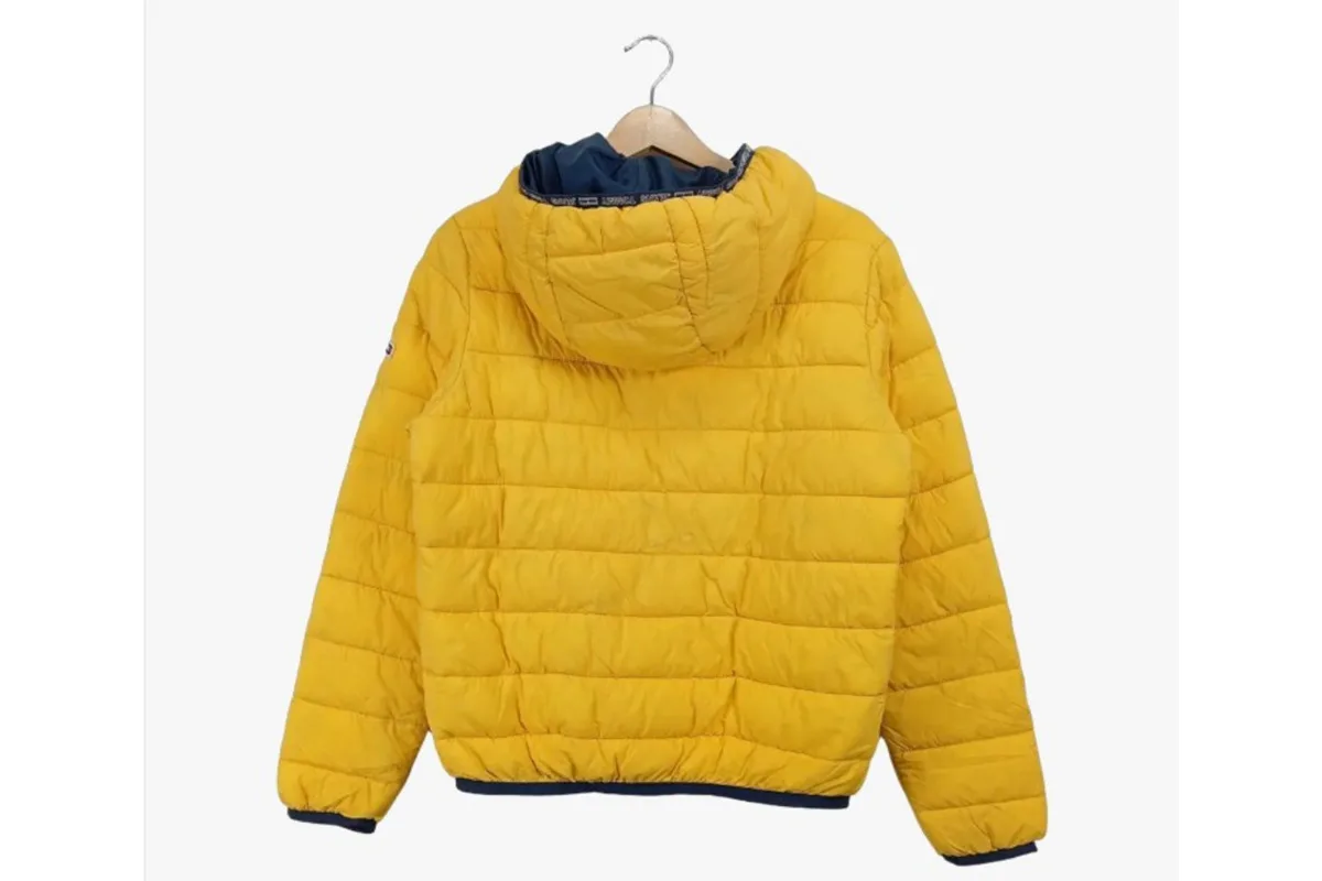 Eine gesteppte, gelbe Jacke mit Kapuze hängt an einem Kleiderbügel vor einem weißen Hintergrund.