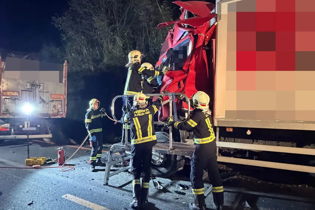 Mehrere Feuerwehrleute arbeiten gemeinsam, um einen Lkw-Fahrer aus einem stark beschädigten Führerhaus zu retten. Der Unfall ereignete sich in der Dunkelheit.