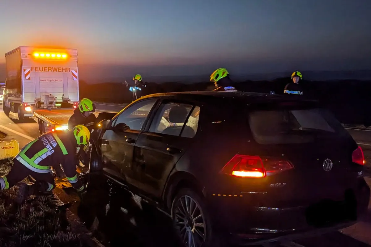 In der Dunkelheit sichern Feuerwehrleute einen schwarzen VW Golf auf einer Autobahn ab. Ein Feuerwehrfahrzeug steht im Hintergrund mit eingeschaltetem Warnlicht.