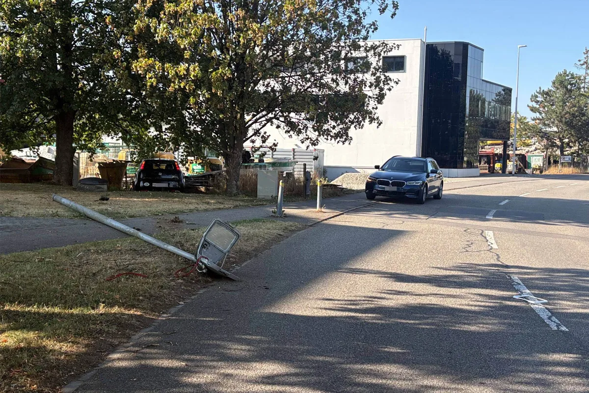 Eine Straße mit einem umgestürzten Laternenmast am Rand. Ein Fahrzeug steht daneben geparkt.