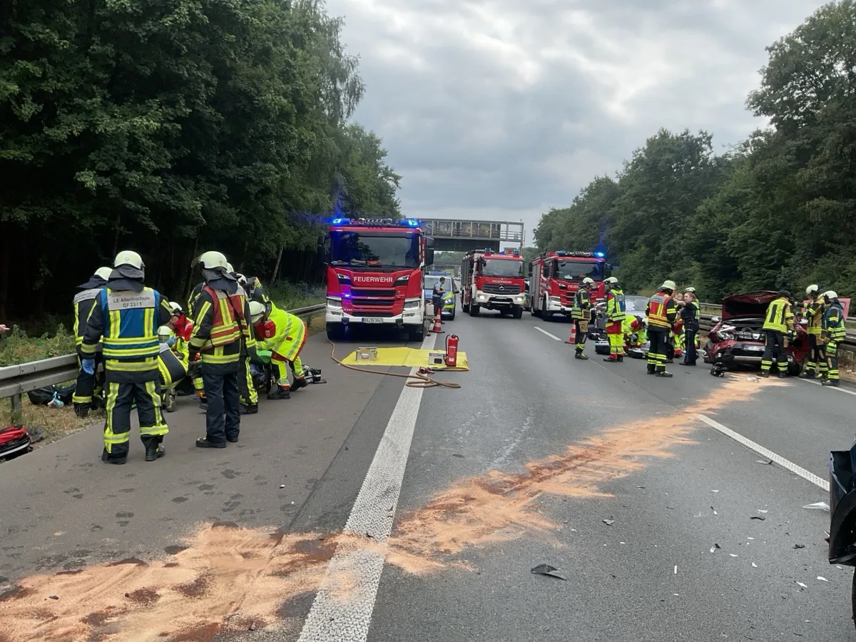 Mehrere Feuerwehrfahrzeuge stehen auf der Autobahn. Feuerwehrleute betreuen Verletzte und sichern die Unfallstelle.